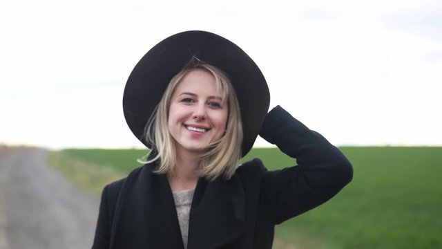 Style blonde woman in hat an coat at springtime countryside