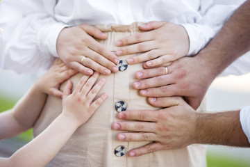 Belly of a pregnant woman. Hands of husband and older child on belly. The concept of the family, the child's expectations and love