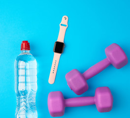 purple plastic kettlebells, a transparent bottle of water and a smart watch
