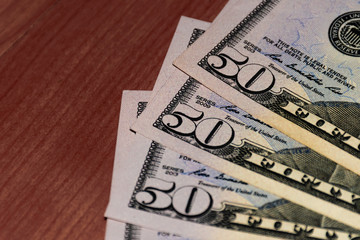 A close-up shot of a stack of several fifty US dollars banknotes on the table