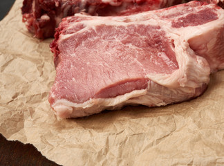 raw juicy pork slices of meat on the rib, food lies on brown parchment paper