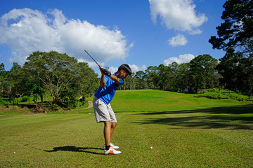 Golfer hitting golf shot with club on course.