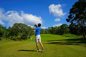 Fototapeta premium Golfer hitting golf shot with club on course.