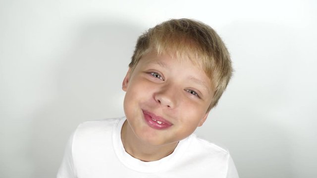 Closeup 4k video portrait of happy cute funny pleased kid making begging and asking face expression isolated at white wall background.