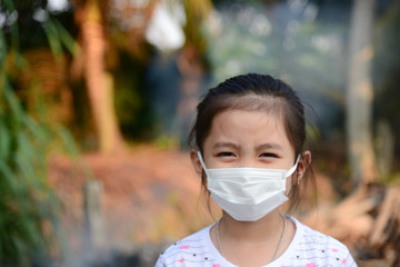 Girl wearing protective face mask with smoke on background.