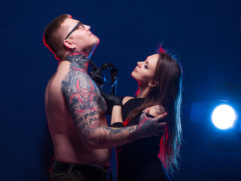 Woman makes a tattoo to her boyfriend. A pair of informal punks lovers. Tattoo master unusual profession. neck tattoo process