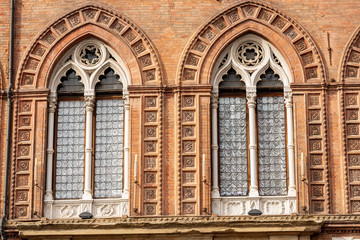 Fototapeta na wymiar Closeup of two mullioned windows (bifore) of the Palazzo d'Accursio, Town hall in downtown of Bologna (XIII century), Piazza Maggiore, Emilia-Romagna, Italy, Europe