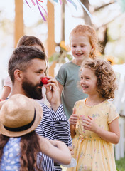 Man with small children sitting on ground outdoors in garden in summer, playing.