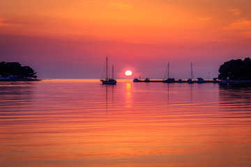 Fototapeta na wymiar Sunset with boat silhouettes on the Adriatic sea. The Green lagoon in Porec - Istria, Croatia, Europe.