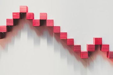 Declining red graphic curve made with wooden boxes. Financial concept