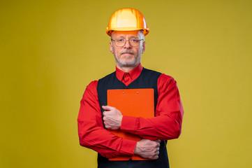 Mature construction supervisor holding a clipboard isolated on yellow background