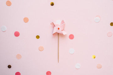 Children's pastel weather vane topper for a cupcake on a pink background with confetti. Birthday festive background