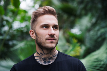 Front view of young man standing in botanical garden.