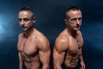 Fototapeta na wymiar Two Muscular man isolated on the black background. Strong male naked torso abs