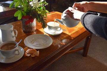 Pouring hot tea into a cup on wooden table background, Traditional english tea