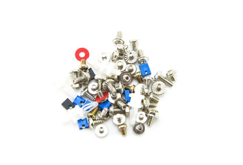 Small bolts, screws and nuts are scattered interspersed with red washers and jumpers in blue and black for the computer. Fasteners for electronics assembly. White isolated background. Close-up.