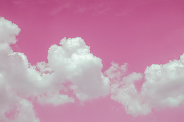 White clouds against the pink sky against a blurred patterned background