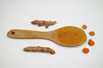 Turmeric powder in a wooden spoon and turmeric powder which is isolated on a white background as an...