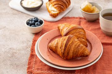 Fresh croissants with blueberries and honey, gray background.