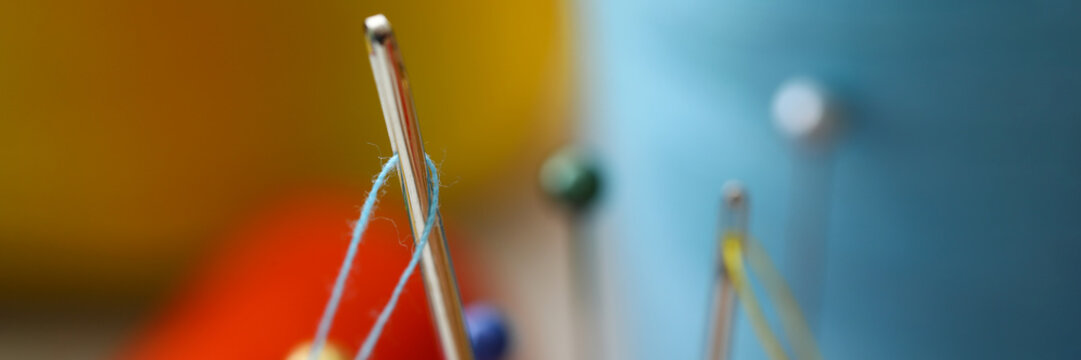 Needle Eye With Piece Of Blue Thread Stick Out Of Pincushion