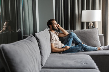 Fototapeta premium Optimistic young man indoors at home on sofa