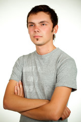 Portrait of a Caucasian young positive guy in a gray shirt and jeans posing on a gray background. Concept of a successful young student or novice employee. Advertising space