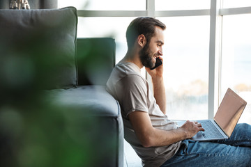 Pleased young man talking by mobile phone.