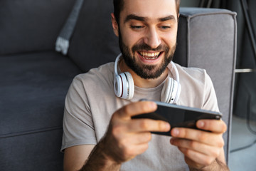 Optimistic young man play games by mobile phone