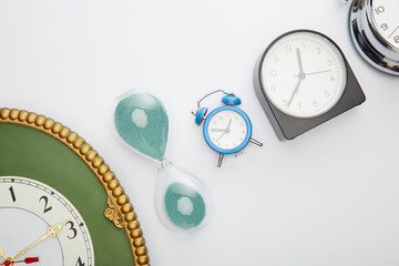flat lay with classic alarm clocks and hourglass on white background