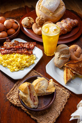 mesa de café da manhã preparada com pães, bacon, ovos e suco de laranja