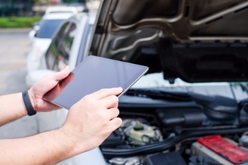 The mechanic is customizing the car with a tablet. Modern technology concepts and the automotive...