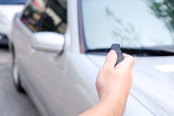 The man’s hand is holding the remote control and then use the new push button to open the car door. Conceptual technology equipment for vehicles.