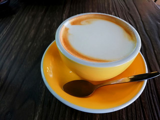 Capucino coffee yellow cup on wooden table backgrounds