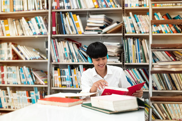Young teenager wearing headphone on her head,read book with interested feeling,at library,blurry...