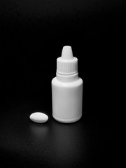 bottle of white and a tablet on black background.