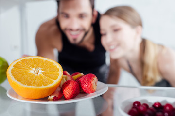 Obraz na płótnie Canvas selective focus of tasty fruits in fridge near happy man and woman