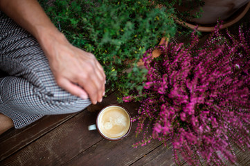 Midsection of woman with coffee sitting outdoors on terrace, resting.
