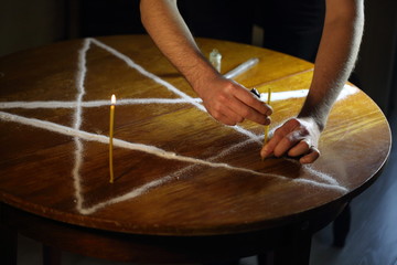 Men's hands set candles on the pentagram symbol