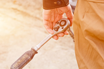 Auto mechanic man with electric screwdriver changing tire outside. Car service. Hands replace tires...