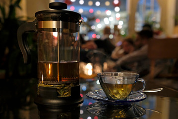 Fresh herbal tea in a transparent tea press in a cozy cafe in the evening
