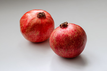 Two ripe, juicy pomegranates on a light background