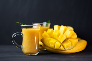 very tasty smoothie with mango, orange and banana in glasses. summer yellow fruit cocktail