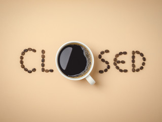 Top view of roasted coffee beans arranged in letters and hot coffee in white coffee cup on light brown background for coffee menus or cafe signs