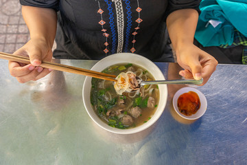 Top view of local woman eating Pho noodle soup