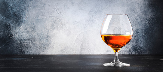 Cognac in a glass, gray background, long banner with copy space