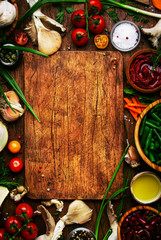 Food cooking background, ingredients for preparation vegan dishes, vegetables, roots, spices, mushrooms and herbs. Cutting board. Healthy food concept. Rustic wooden table, top view