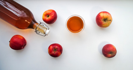 Top view of a bottle and glass with natural apple juice on white, banner. Homemade apple juice.