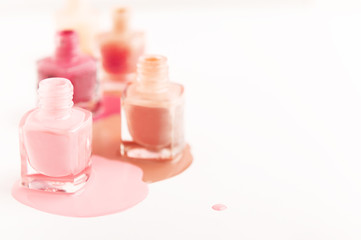 Glass containers with liquid and splatters of nail polish on white background. Beauty and nail saloon procedure concept. Copy space in right side. Open unbranded glass bottles. Soft focus