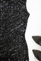 Women's black dress with sequins   and shoes on light background. Top view. Stylish party accessories.