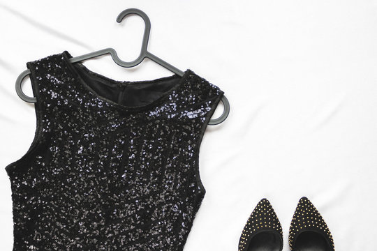 Women's Black Dress With Sequins On Hanger And Shoes On Light Background. Top View. Stylish Party Accessories.